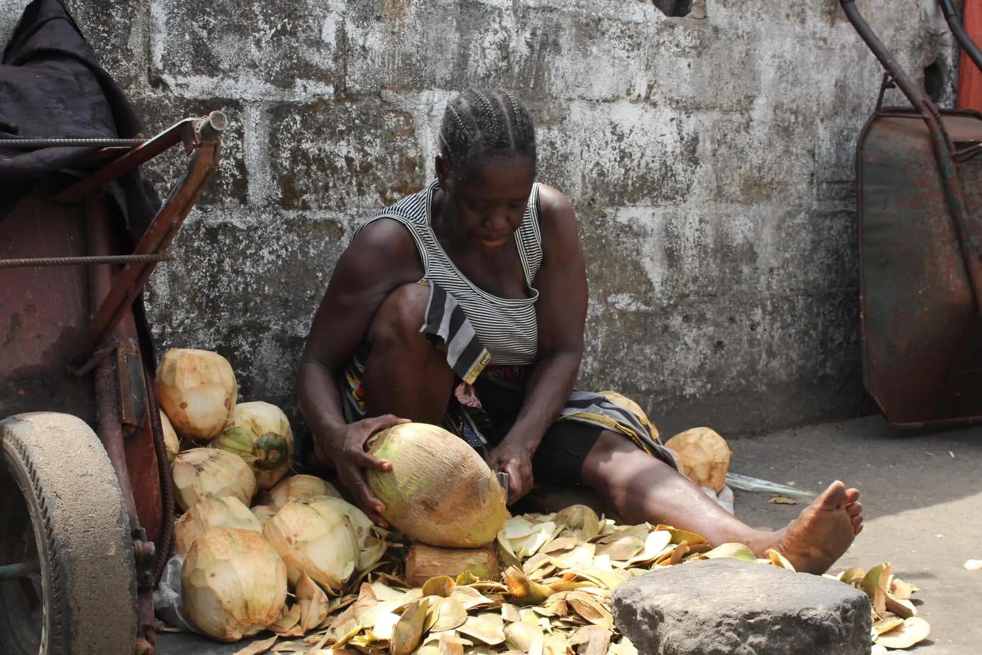 Woman opening coconuts by hand on a roadside