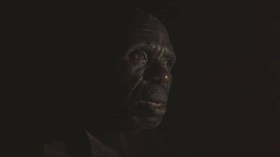 Portrait of a man lit by a single low light in darkness